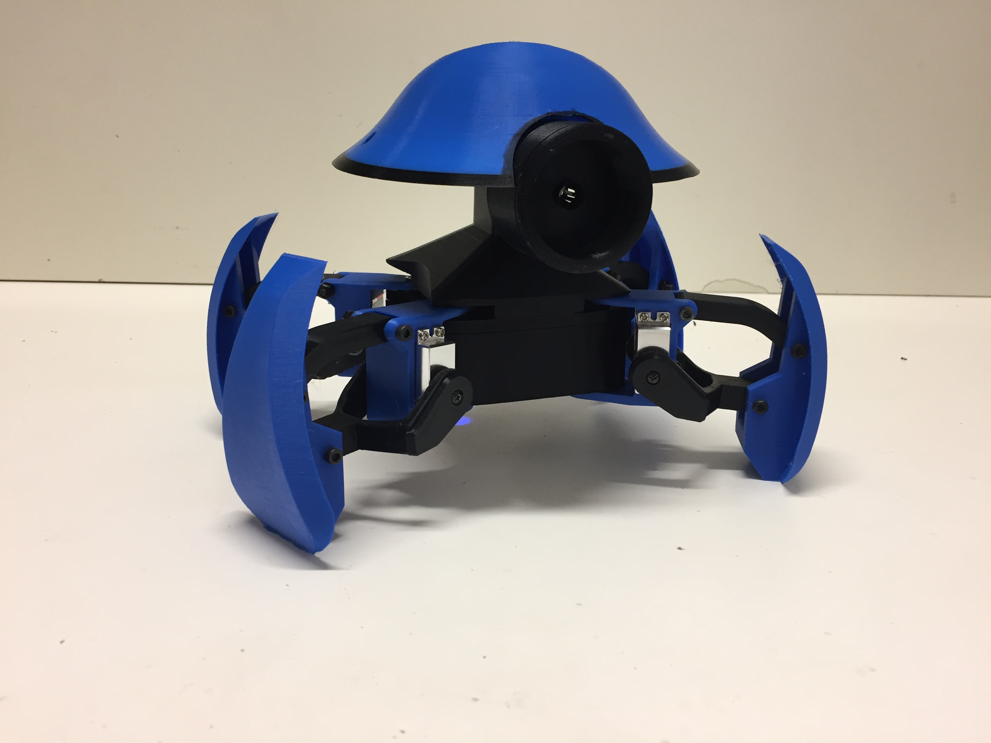 The assembled iOlly quadruped photographed on the workbench, with visible printed layers and servo horns